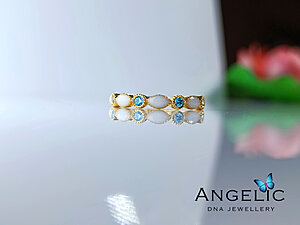 The Angelic Marquise Genuine Birthstones Ring features a design with alternating blue and clear gemstones set in gold-tone metal, showcasing a delicate composition suitable for various occasions.