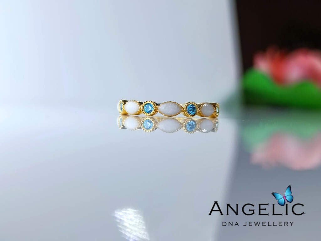 The Angelic Marquise Genuine Birthstones Ring features a design with alternating blue and clear gemstones set in gold-tone metal, showcasing a delicate composition suitable for various occasions.