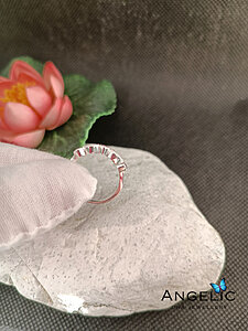 The Angelic Two Marquisette Three Genuine Birthstones DNA Ring features a unique design with three marquis-shaped genuine birthstones set in a polished silver band, shown resting on a decorative stone.