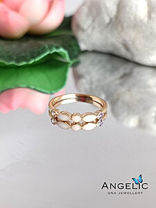 The Angelic Two Marquisette Three Genuine Birthstones DNA Ring in gold tone features a delicate design with marquise-shaped elements and three genuine gemstones, presented elegantly beside a decorative leaf.