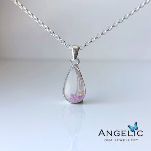 A silver teardrop pendant necklace with a translucent gemstone containing delicate purple flowers, displayed on a reflective surface with the brand name 'Angelic DNA Jewellery' visible in the corner.