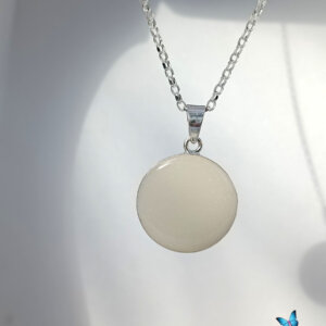 Silver necklace with a round, smooth pendant displayed against a light background. Ideal for showcasing minimalist jewelry designs.